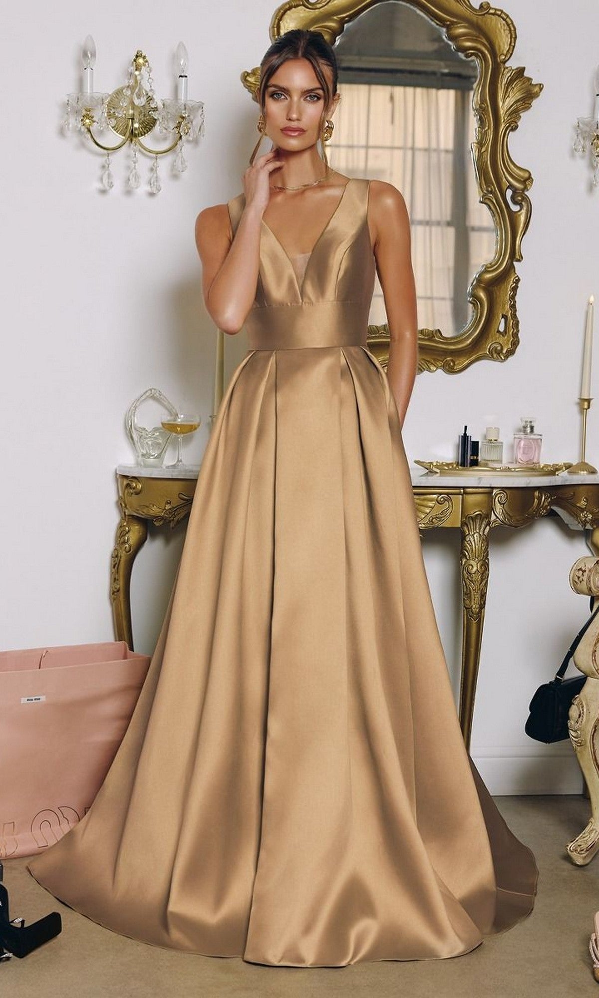 A woman stands indoors wearing the Amoris T814 Sleeveless Long Mikado Prom Dress, posing in front of an ornate mirror and vanity table.